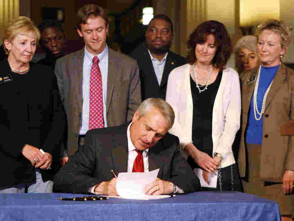 Colo. Gov. Bill Ritter, seated, signs a tenure bill that will judge teachers on student performance.