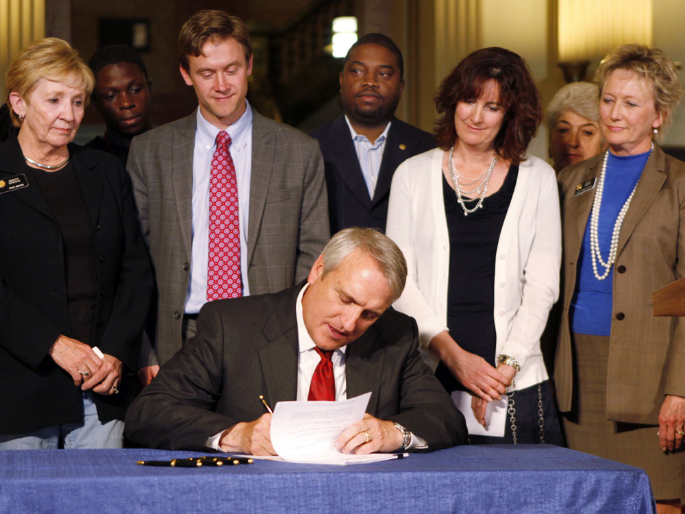 Colo. Gov. Bill Ritter, seated, signs a tenure bill that will judge teachers on student performance.