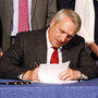 Colo. Gov. Bill Ritter, seated, signs a tenure bill that will judge teachers on student performance.