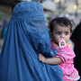 A burqa-clad woman carries a child through Kabul's old town A burqa-clad woman carries a child through Kabul's old town