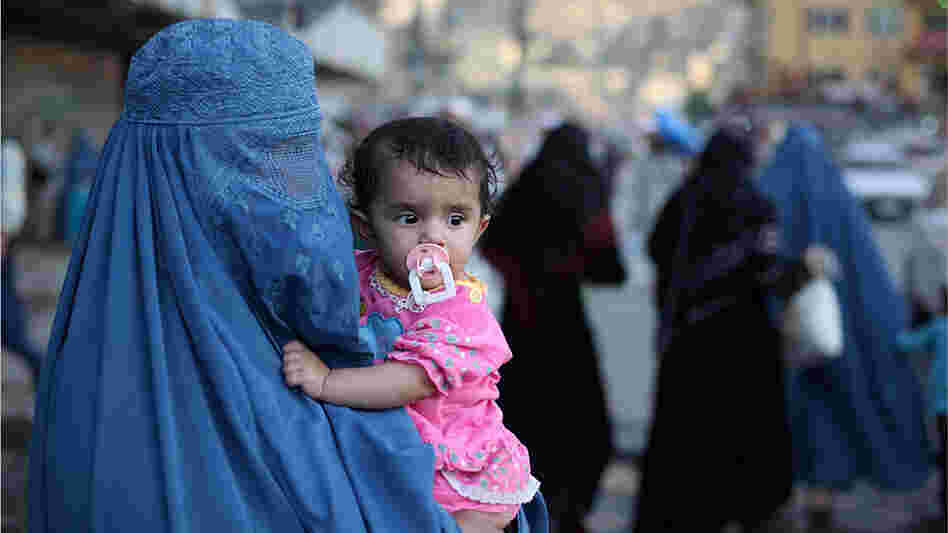 A burqa-clad woman carries a child through Kabul's old town