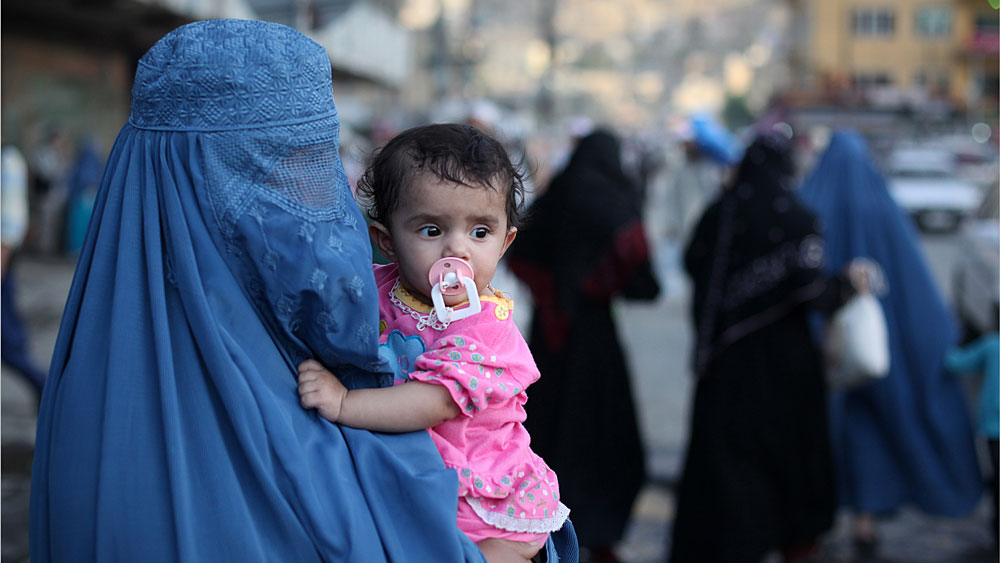 A burqa-clad Afghan woman carries a child through the old town area of Kabul last month. Afghan women worry that peace talks with the Taliban might result in a loss of rights they had slowly regained after the militants' harsh and restrictive rule.