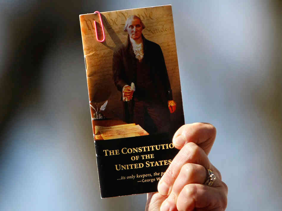 A rally participant holds up a pocket-sized copy of the U.S. Constitution.