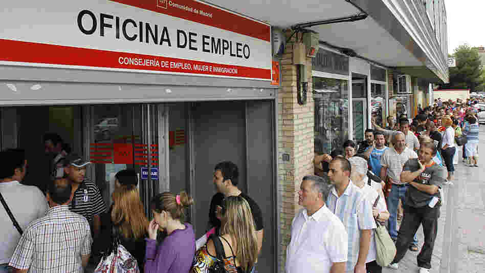 People stand in line outside a government job center in Madrid