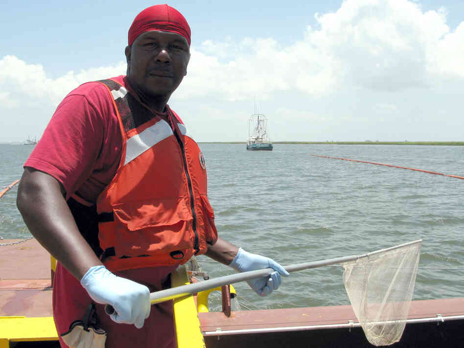 Kinte Walker stands on a boat in Lake Pontchartrain, waiting to scoop up tar balls.