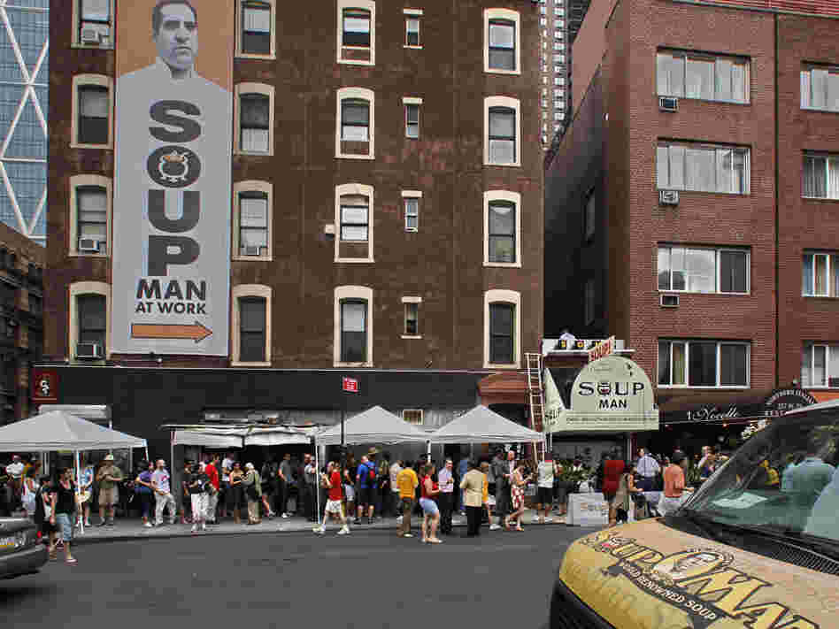 About 100 people stand in line for the reopening of the Original SoupMan gourmet takeout shop.