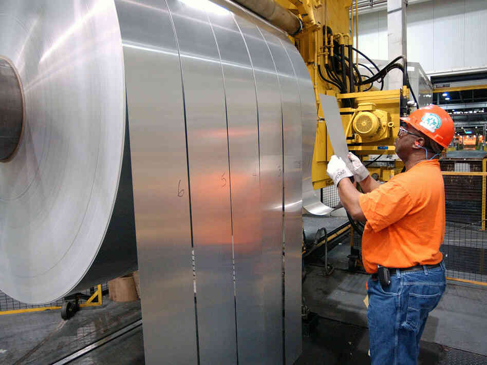 An employee inspects finished rolls of aluminum at an Alcoa facility