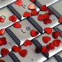 A computer keyboard covered in small red hearts.
