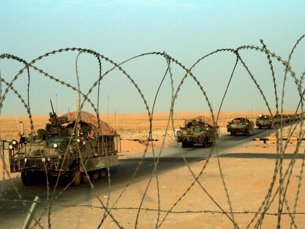 A column of Stryker armored vehicles carrying Army troops crosses the border from Iraq into Kuwait.