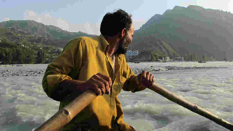 An oarsman navigates his inner-tube boat across the raging Swat River