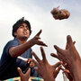 Pakistanis displaced by flooding reach for food aid thrown by a volunteer. Pakistanis displaced by flooding reach for food aid thrown by a volunteer.