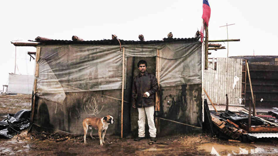 A man stands in front of a shack he built at a temporary camp Penco's port in Concepcion
