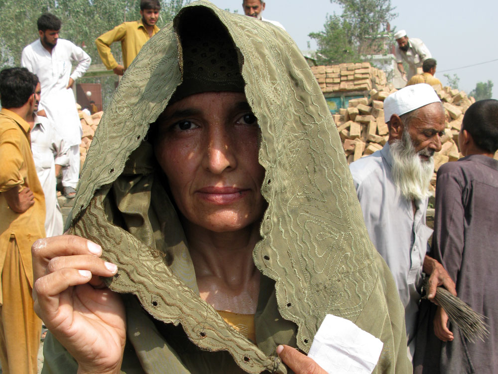Wajahat Bibi, a mother of six, lifts her veil to have her photo taken.