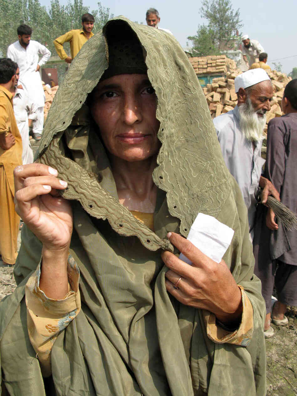 Wajahat Bibi, a mother of six, lifts her veil to have her photo taken.