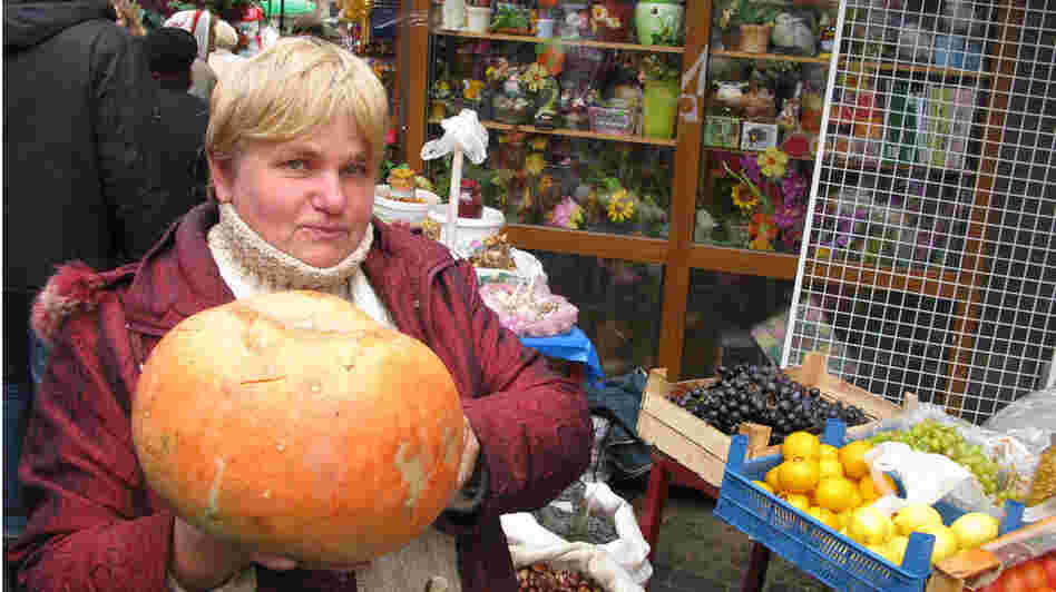 Vegetable seller Olesya Vladymyrovna holds a pumpkin