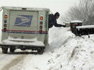 A letter carrier delivers mail in a snowstorm. A letter carrier delivers mail in a snowstorm.