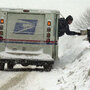 A letter carrier delivers mail in a snowstorm.