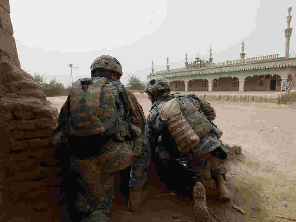 Members of the 101st Airborne Division take cover behind a wall 