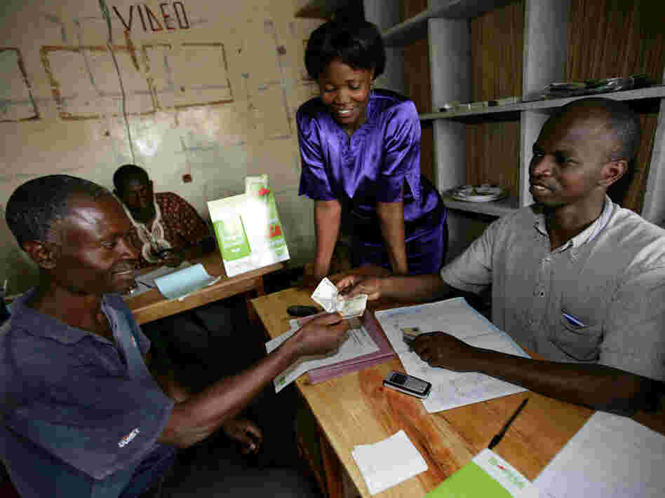 An M-PESA agent helps a client complete a transaction
