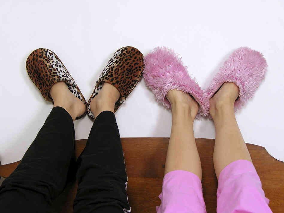 An image of friends slippers as they lie on a bed chatting.