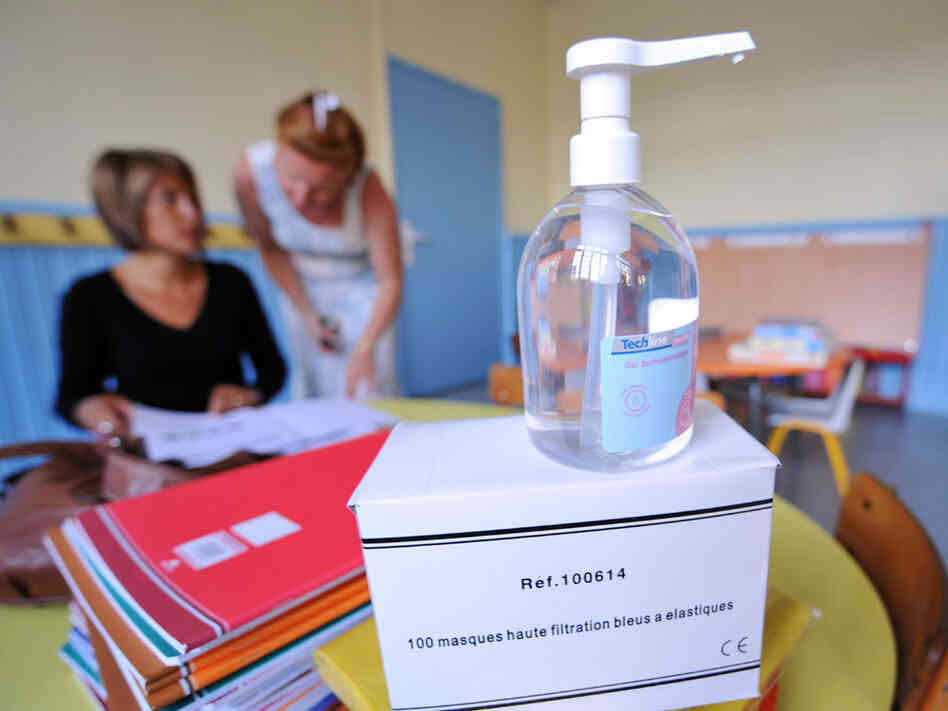 A bottle of alcohol hand sanitizer sits in a classroom.