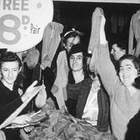 Women hold up nylon stockings in a sale in the 1950s.