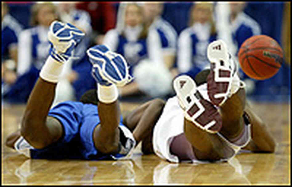 The heels of four basketball players are shown as they chase a loose ball.