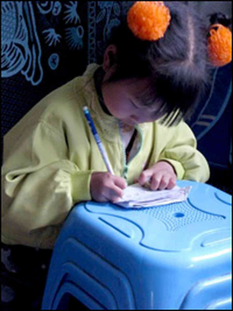 A young Chinese girl in a housing camp practices writing. Photo: Melissa Block, NPR. A young Chinese girl in a housing camp practices writing. Photo: Melissa Block, NPR.