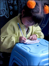 A young Chinese girl in a housing camp practices writing. Photo: Melissa Block, NPR.