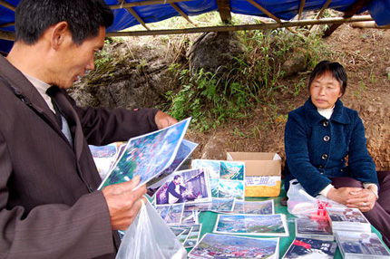 Local vendor Mu Zhenxian lost 16 relatives in the quake. She now sells photos and DVDs of earthquake destruction on a hill overlooking the city of Beichuan, China. Photo: Andrea Hsu, NPR.