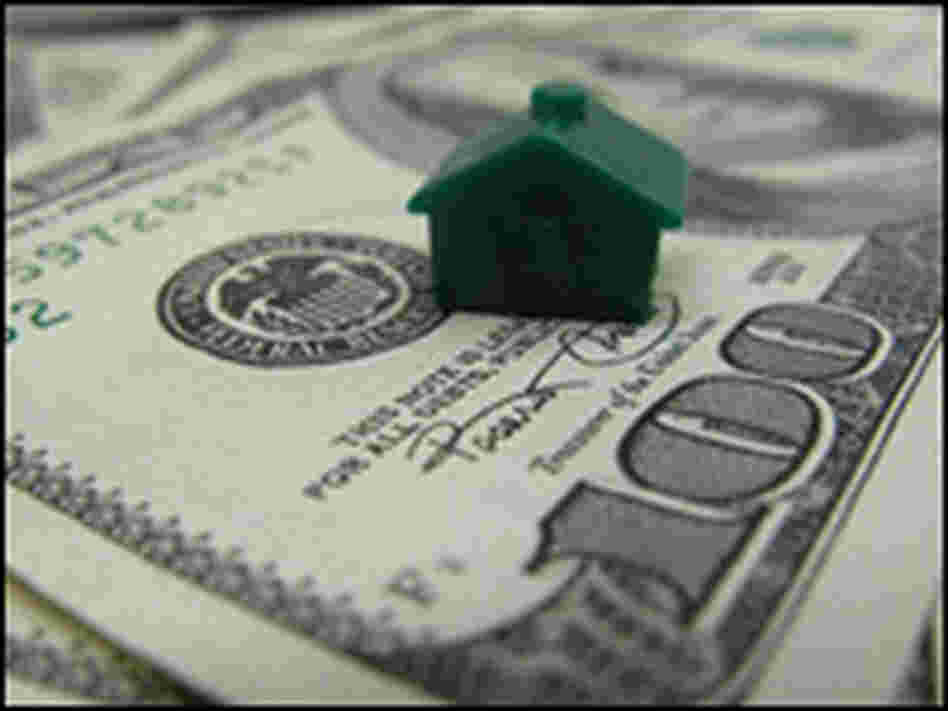 A green plastic Monopoly house sits on a $100 bill. A green plastic Monopoly house sits on a $100 bill.