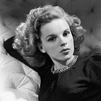A 1942 photo of Judy Garland sitting on a couch.