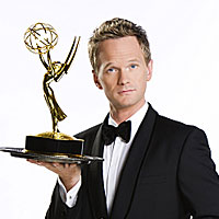 Neil Patrick Harris, host of this year's Emmy ceremony, wears a tuxedo and holds up an Emmy statuette.