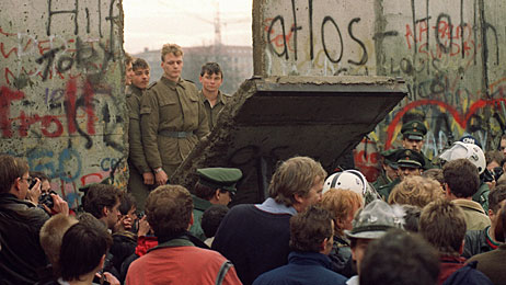 A crowd watches on November 11, 1989 as border guards demolish a piece of the Berlin Wall.