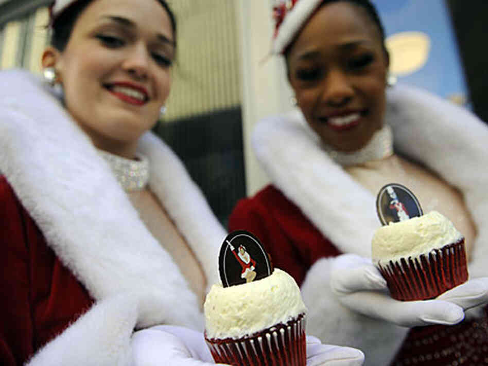 Two Rockettes display two Rockette Red Velvet cupcakes. Two Rockettes display two Rockette Red Velvet cupcakes.