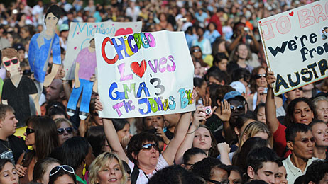 Fans hold up signs at a Jonas Brothers concert.
