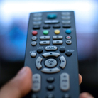 a thumb pressing a remote control.