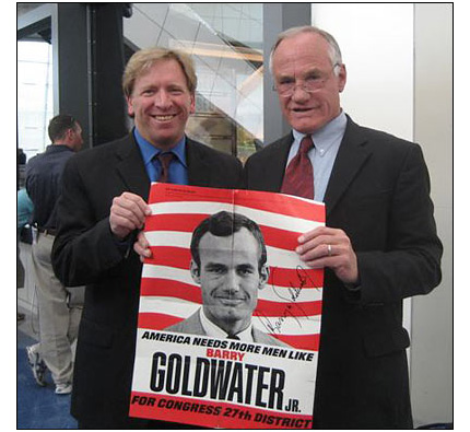 Ken Rudin and Barry Goldwater hold up a Goldwater campaign poster.