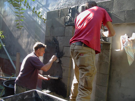 applying stucco to cinder block carcass of fountain