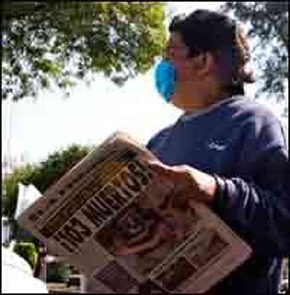 A pedestrian reads a newspaper, which headline states that up to 103 deaths due to the swine flu, A pedestrian reads a newspaper, which headline states that up to 103 deaths due to the swine flu,