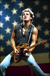 Bruce Springsteen plays guitar in 1985, backed by the stars and stripes.