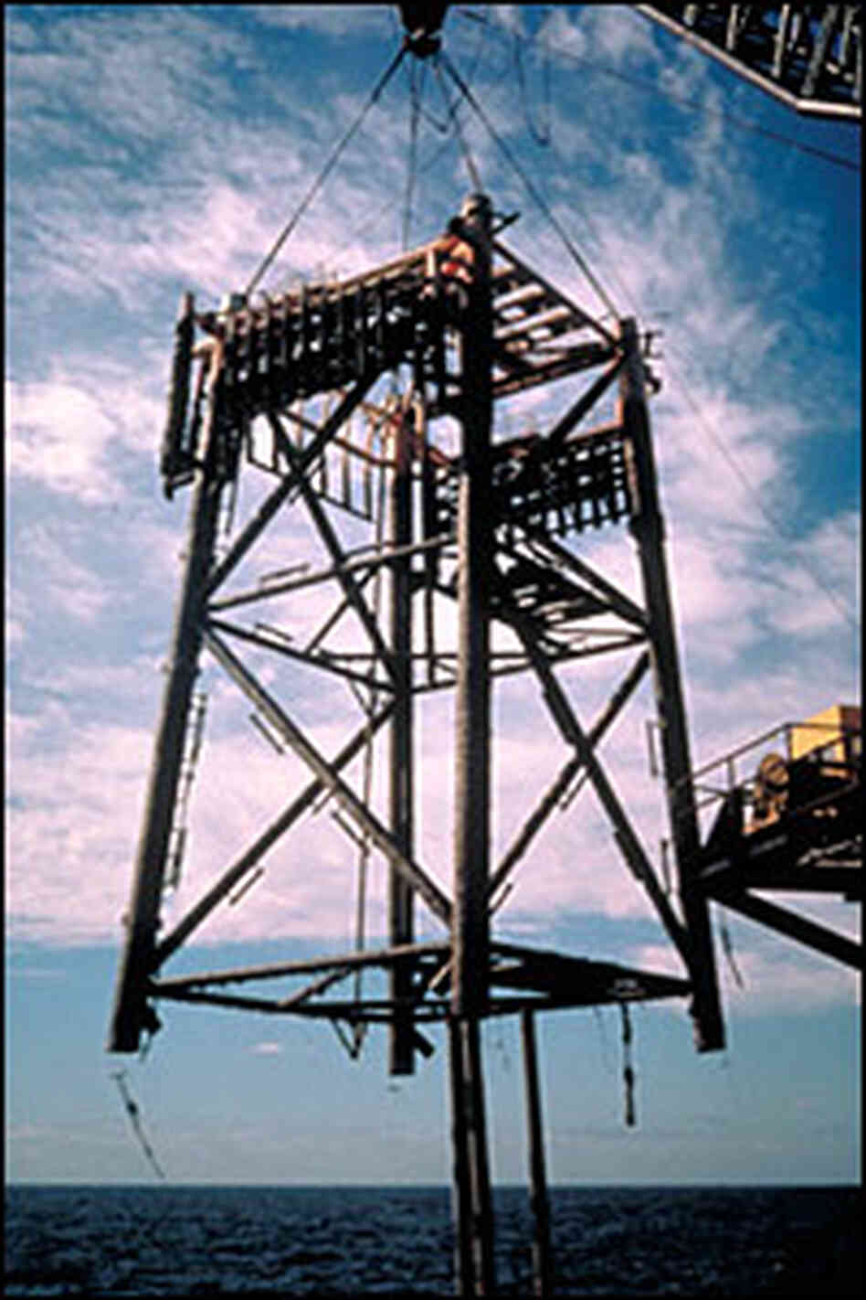 A crane lowers part of an oil plaform at an offshore rig. Credit: Minerals Management Service A crane lowers part of an oil plaform at an offshore rig. Credit: Minerals Management Service