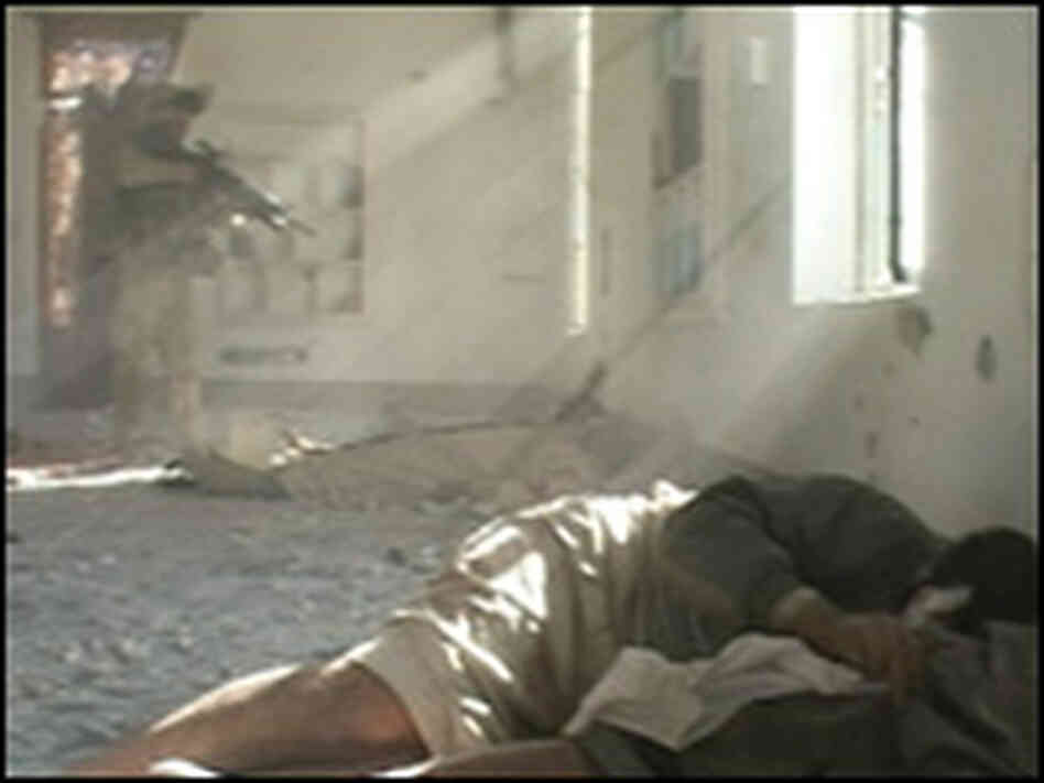 A Marine raising his rifle in the direction of Iraqis on the floor of a mosque in Fallujah.. A Marine raising his rifle in the direction of Iraqis on the floor of a mosque in Fallujah..