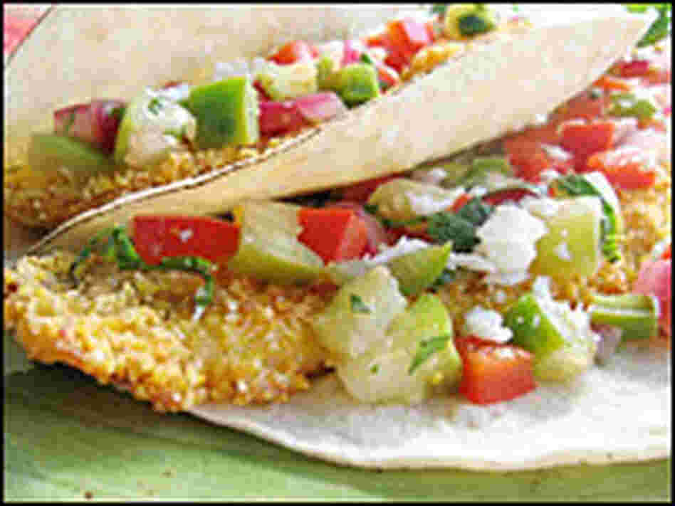 The fish taco is made by placing hot, crispy fried fish on a lightly charred corn tortilla