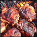 Marinated chicken meat sizzles on a grill. T. Susan Chang for NPR
