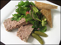 Slices of pate with a salad, toast points and cornichons