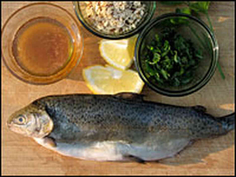 A fresh trout sits on a cutting board with other ingredients for Pan-Fried Trout With Brown Butter