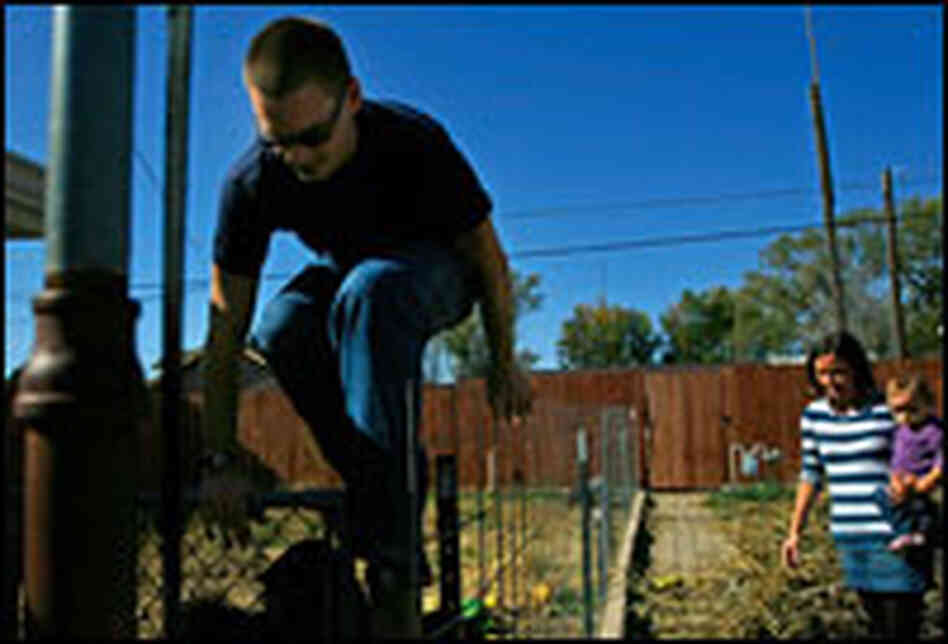 Tyler Jones climbs out of his dog run as his wife, Carol Morrow, and their daughter look on.