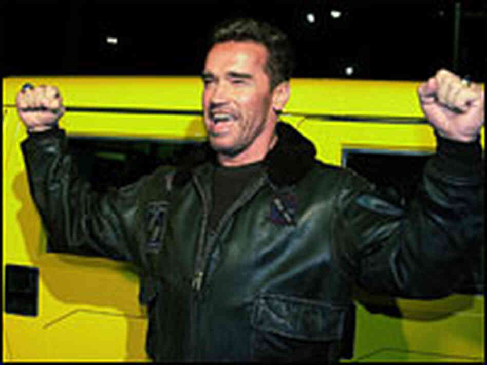 Arnold Schwarzenegger poses by his yellow Hummer
