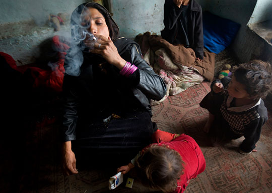 Surrounded by her children, Karima, 30, smokes heroin and opium in her one-room home in Kabul.